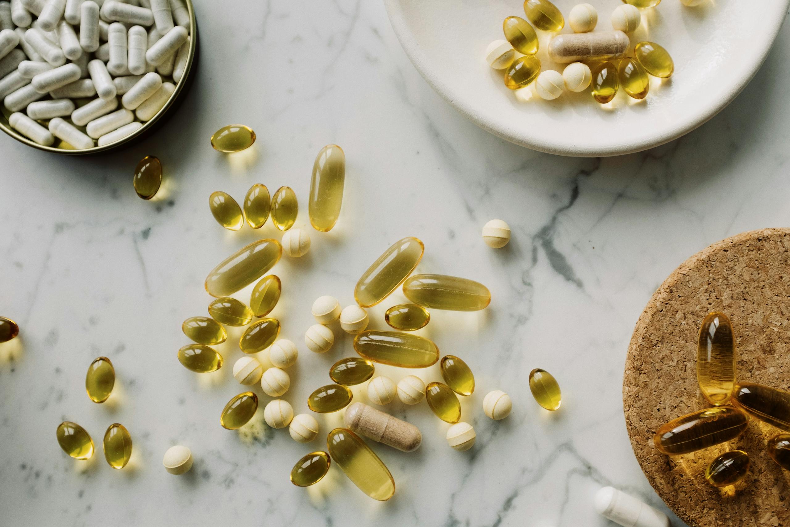 A collection of supplements and pills scattered on a marble surface, showcasing healthcare essentials.