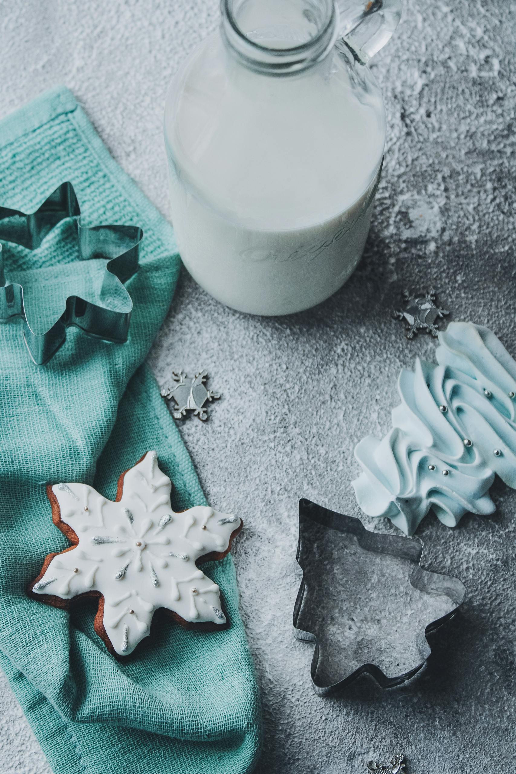 Top view of a winter themed cookie arrangement with milk and baking items.