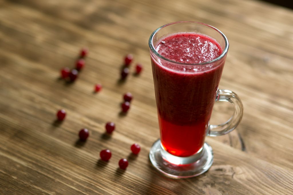 A tall glass of vibrant cranberry juice on a rustic wooden table.