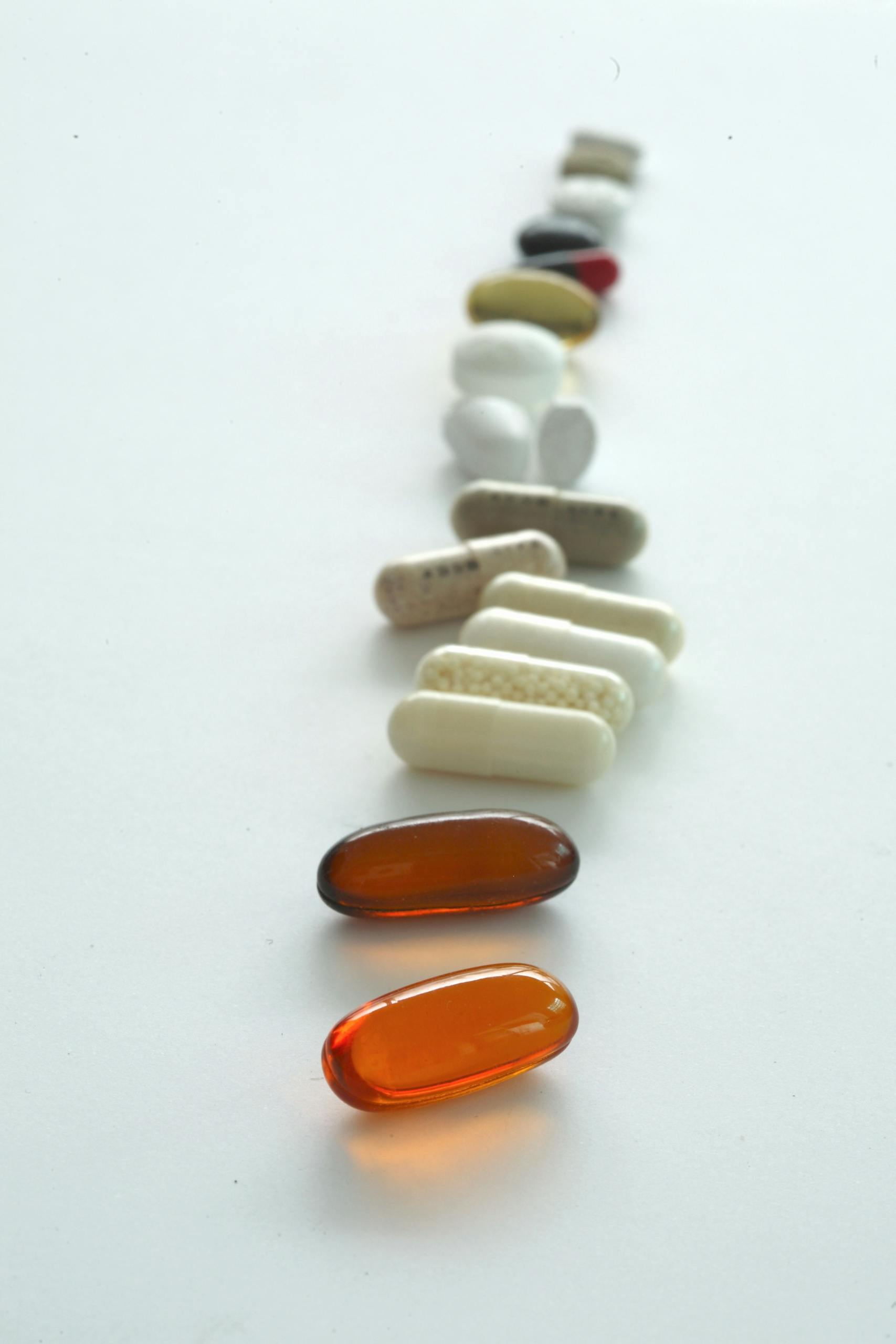 A vertical arrangement of multicolor tablets and capsules on a white background, representing healthcare.