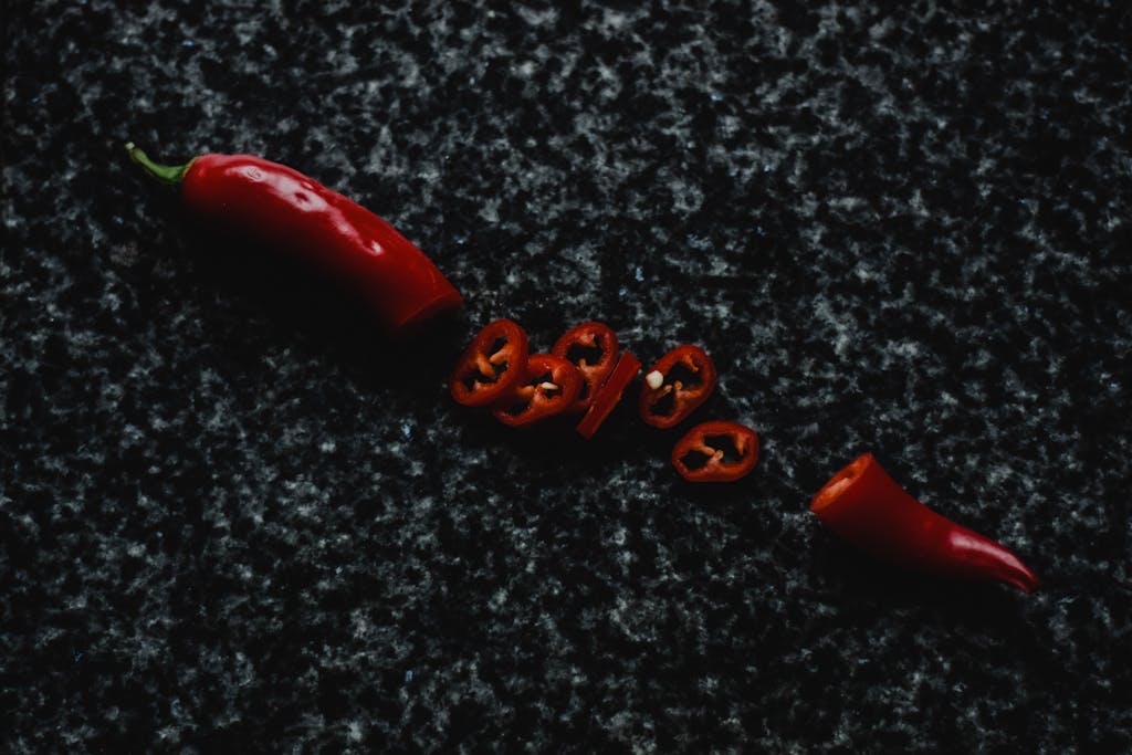 Top view of a sliced red chili pepper on a dark marble background, showcasing spicy and vibrant food elements.