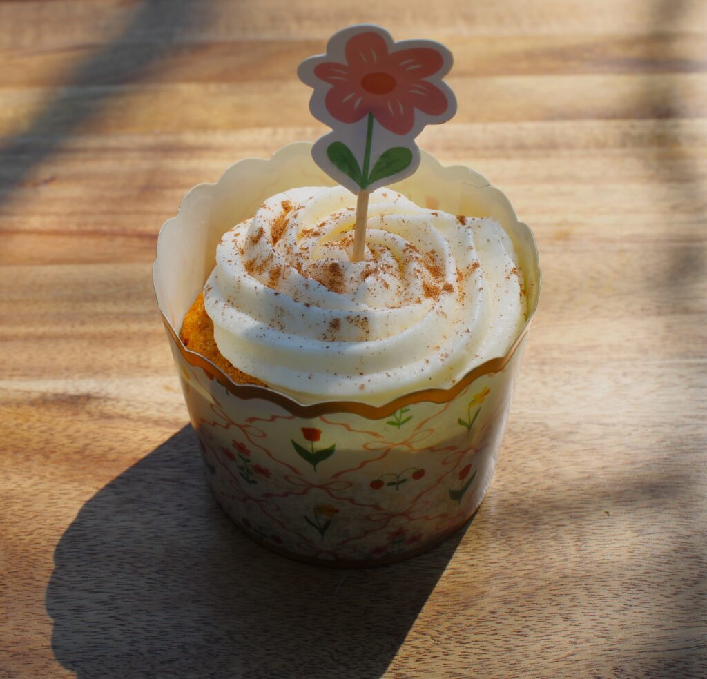 Fresh milled carrot muffin with frosting and a flower. 