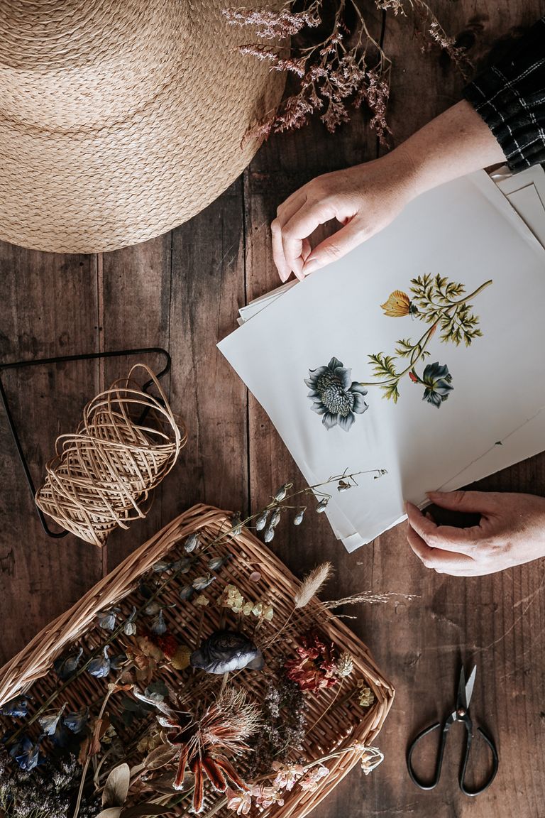 Top view of floral handicraft with dried flowers on wooden table, showcasing creativity.