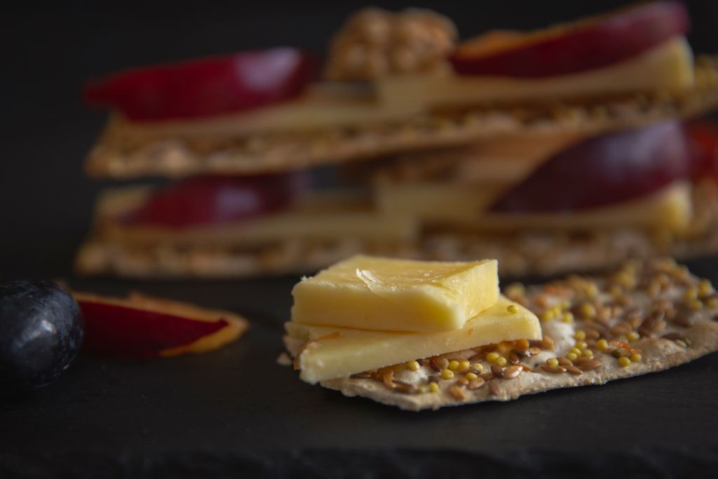 Appetizing close-up of cheese slices on seeded crackers with fresh fruits, perfect for gourmet presentations.