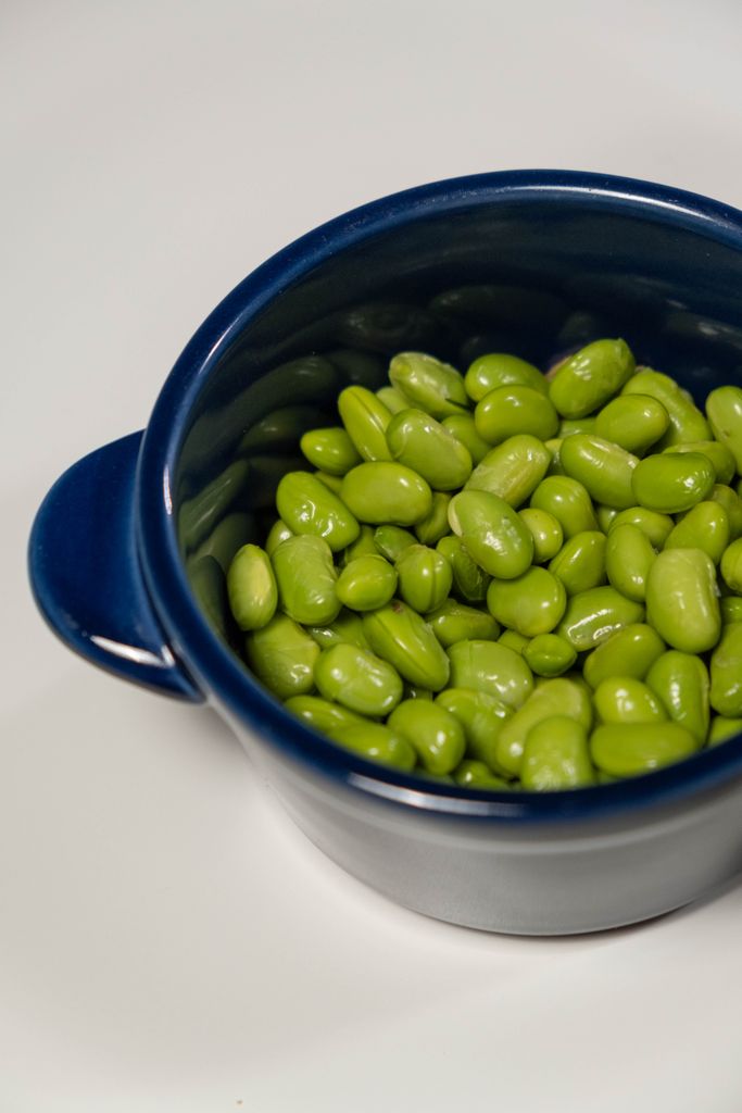 Close-up of fresh green edamame beans in a vibrant blue bowl, perfect for healthy eating.