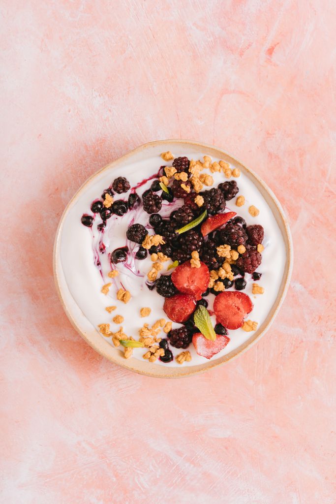 Healthy yogurt bowl topped with fresh berries and crunchy granola on a textured background.